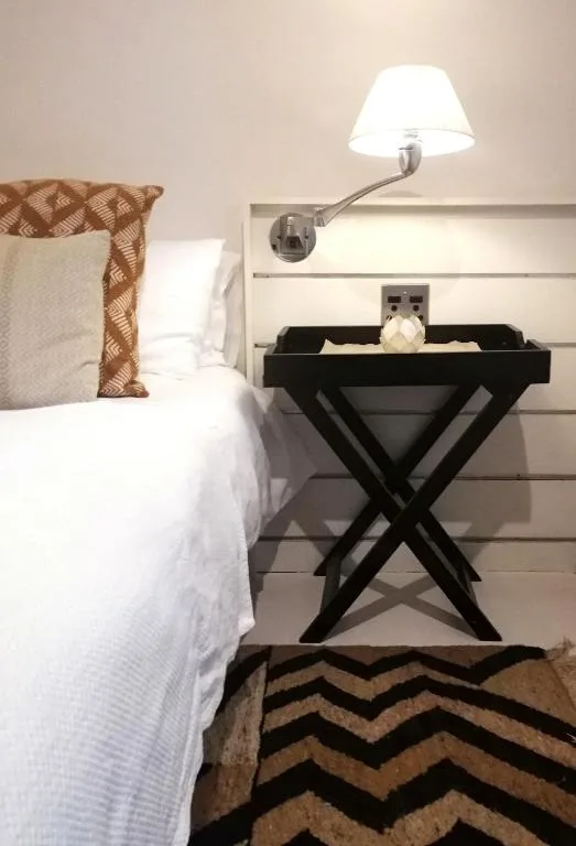 Bed with white linens and patterned pillows beside black nightstand