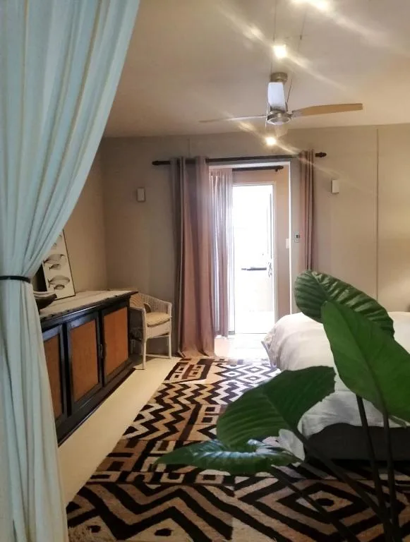 Bedroom with bed, desk, ceiling fan, and glass door opening to garden