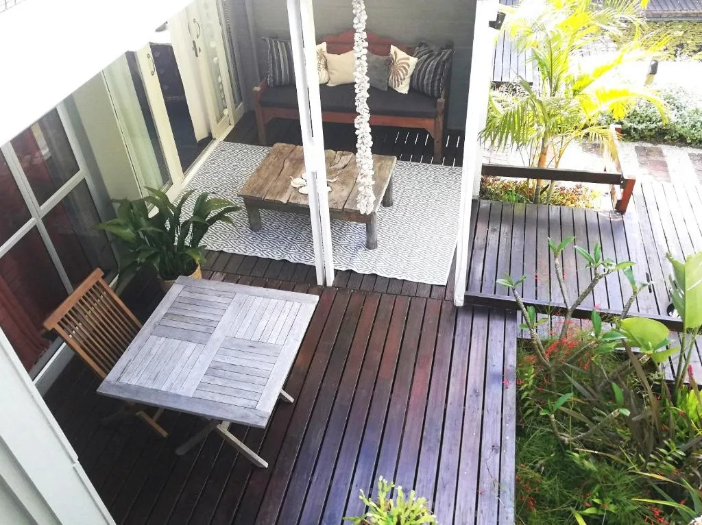 Wooden deck with outdoor furniture and garden views, connecting to lounge area