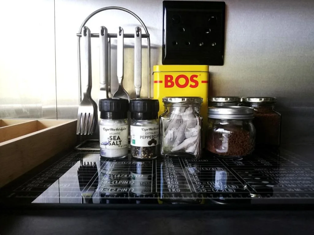 Kitchen counter with sea salt, spices, cooking utensils, and storage jars