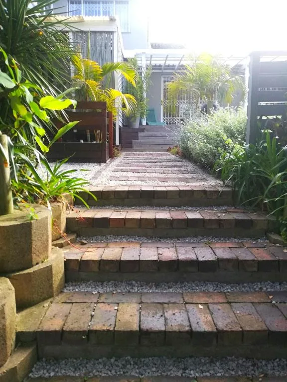 Brick pathway leading through lush tropical garden with palm plants and gates