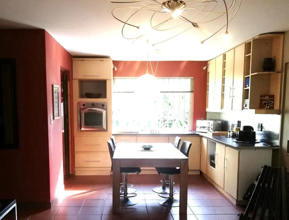 Modern kitchen with red walls, wooden cabinetry, and central dining table