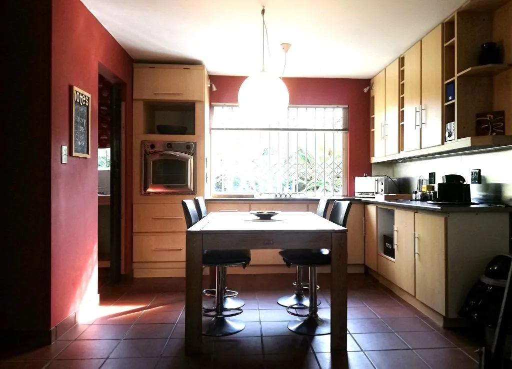 Modern kitchen with red accent walls, wooden cabinetry, and central island seating
