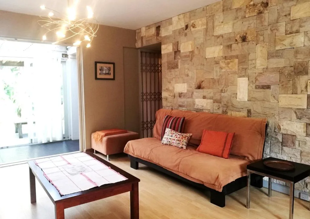 Modern lounge with orange sofa, stone accent wall, and natural light