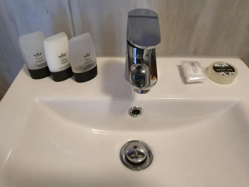 White bathroom sink with chrome faucet and luxury amenities displayed