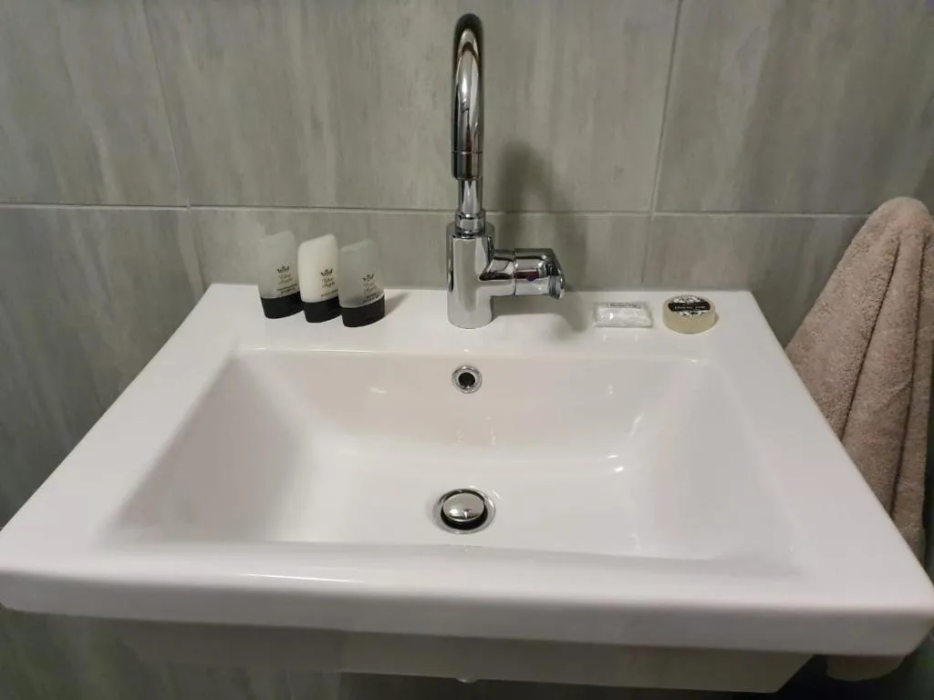 Clean white bathroom vanity sink with chrome faucet and toiletries