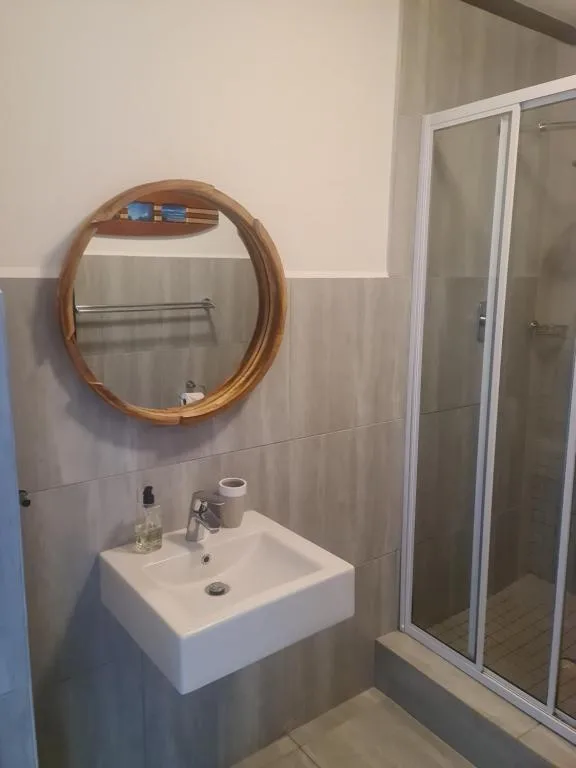 Modern bathroom with white wall-mounted sink and wooden round mirror