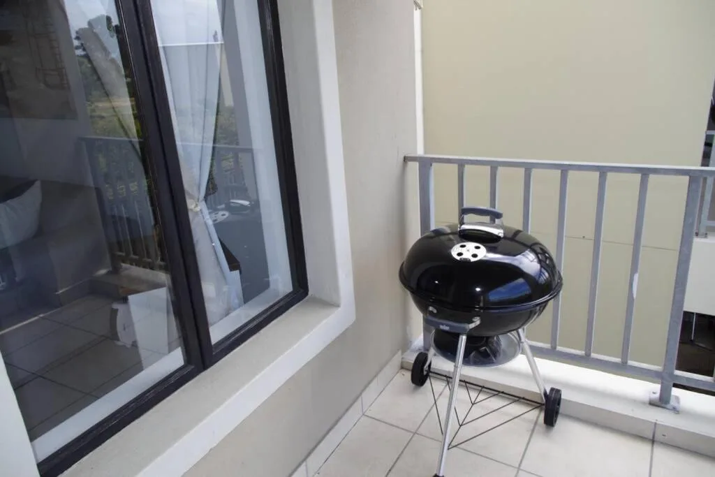 Black kettle braai grill on tiled balcony with metal railings