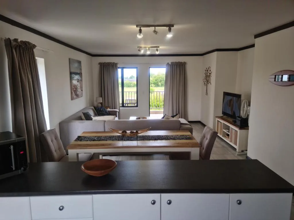 Open-plan lounge with dining table and TV area, garden views through French doors