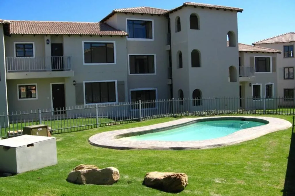 Oval swimming pool in manicured garden with contemporary apartment buildings