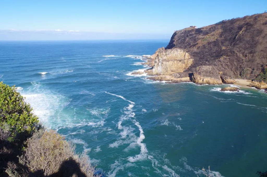 Dramatic coastal cliffs and turquoise ocean waves under clear blue sky
