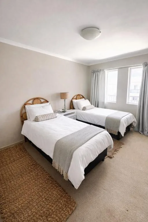Bright bedroom with two single beds, woven headboards, white bedding