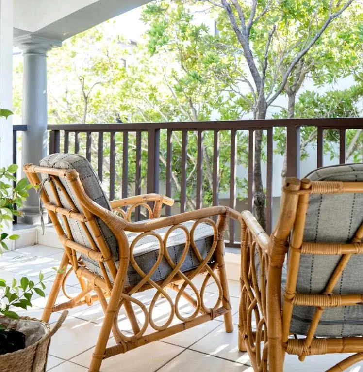 Covered patio with wicker chairs and tree views overlooking garden