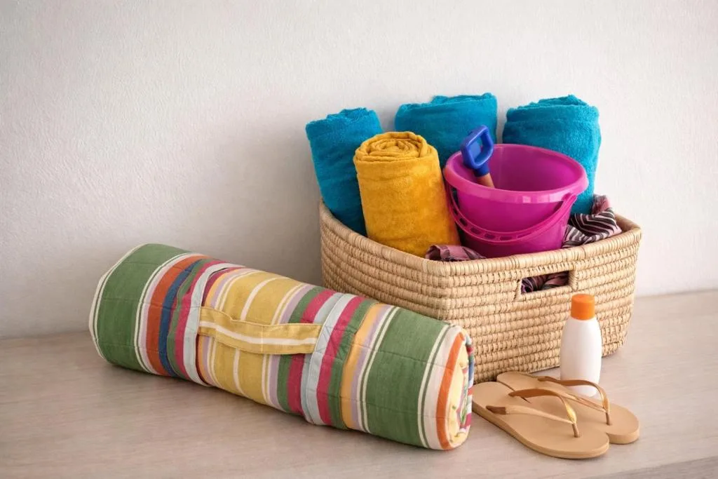 Colorful beach towels, baskets, and accessories arranged on wooden surface