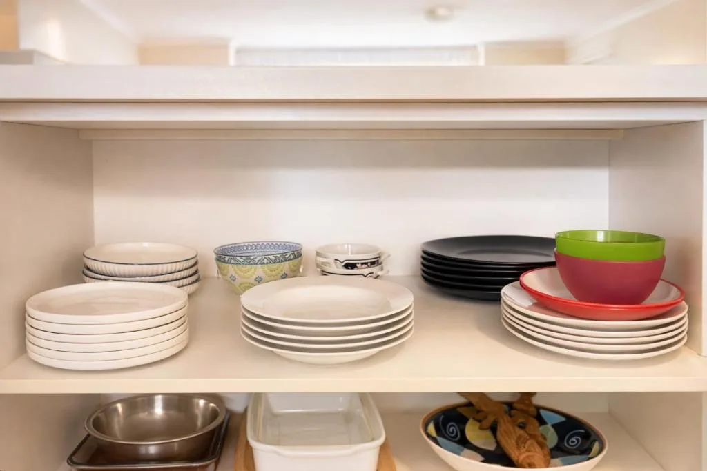 Kitchen cupboard shelf with organized plates, bowls, and dining dishes