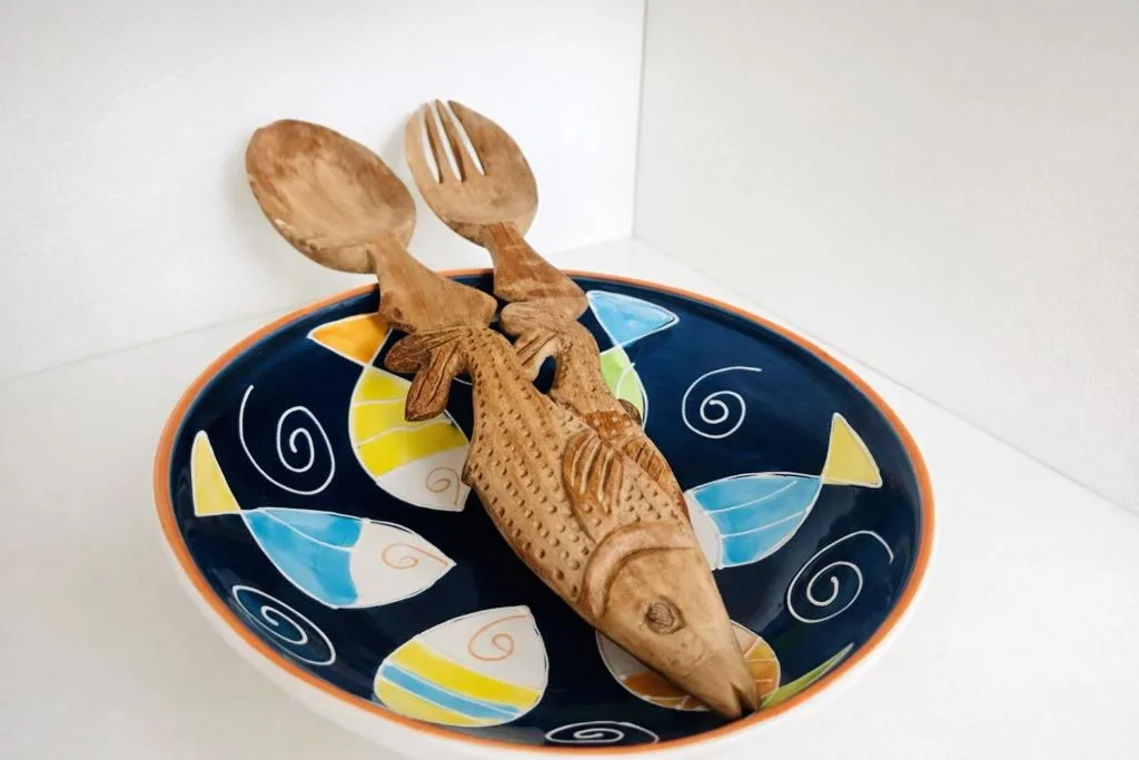 Wooden crocodile utensil holder with spoon and fork on decorative plate