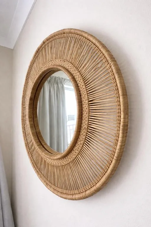 Woven rattan oval mirror with natural fiber frame on white wall