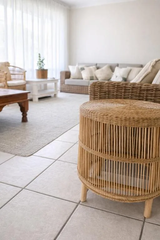 Bright lounge with woven furniture, sofa, and large windows overlooking garden