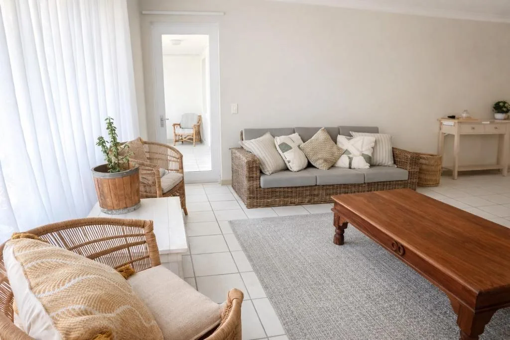 Bright lounge with wicker seating, gray sofa, and wooden table