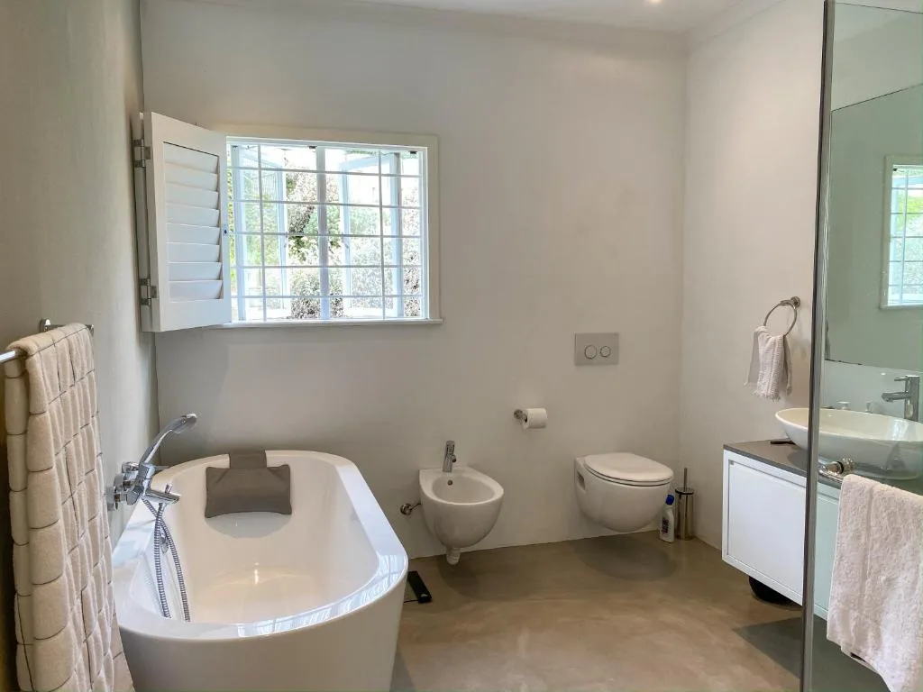 Modern bathroom with freestanding tub, bidet, toilet, and large window