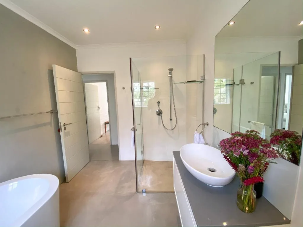 Modern bathroom with freestanding tub, walk-in shower, and fresh flowers