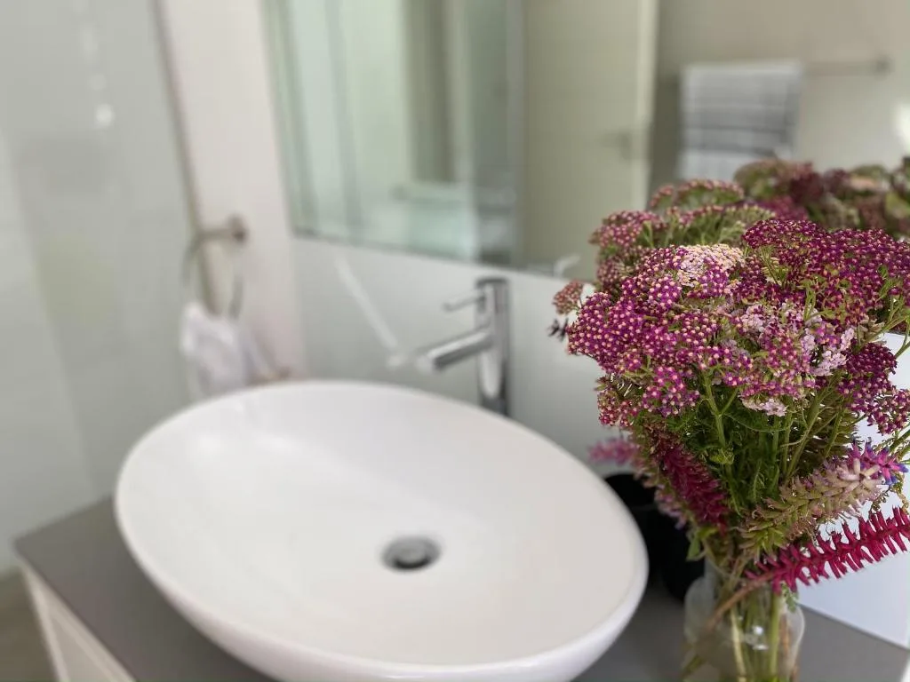 Modern round white sink with fresh purple flowers in vase nearby