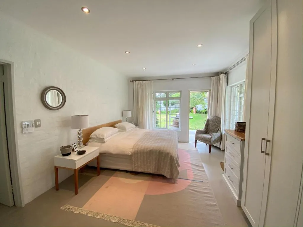 Spacious bedroom with queen bed, French doors opening to garden views