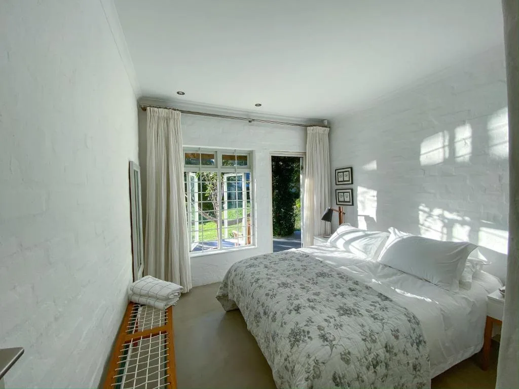 Bright bedroom with double bed, French doors opening to garden view