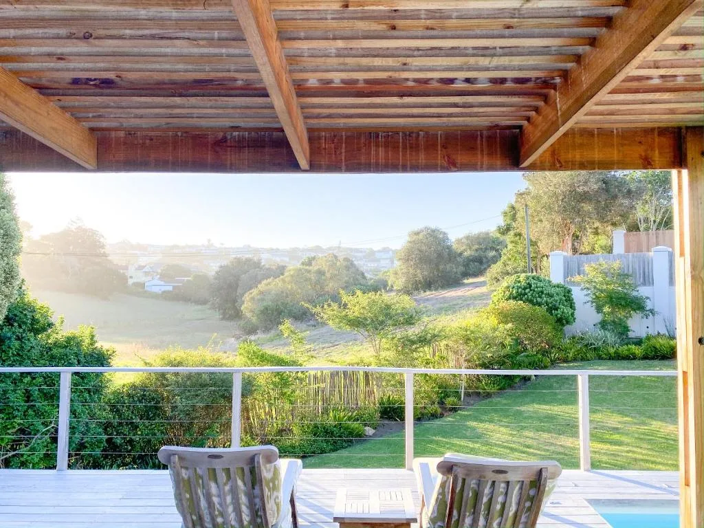 Wooden deck with chairs overlooking green valley landscape and distant hills