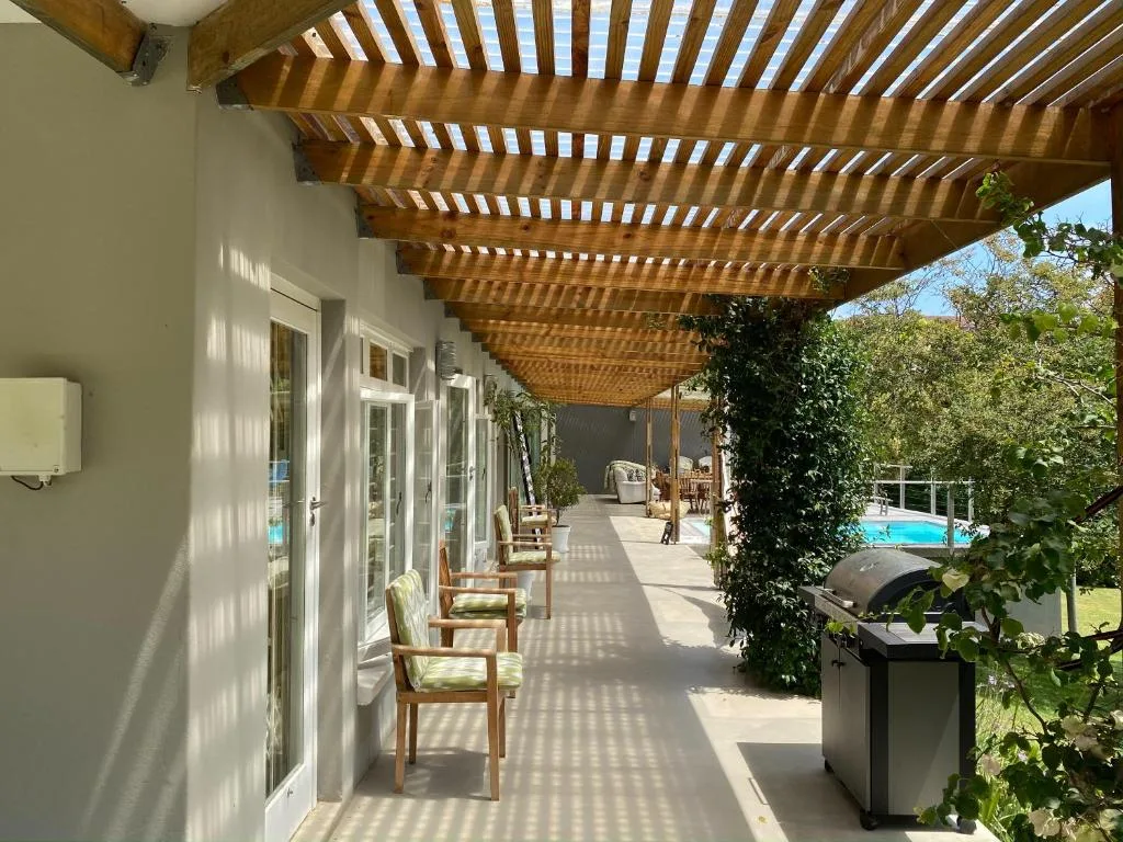 Covered wooden pergola deck with seating and pool view