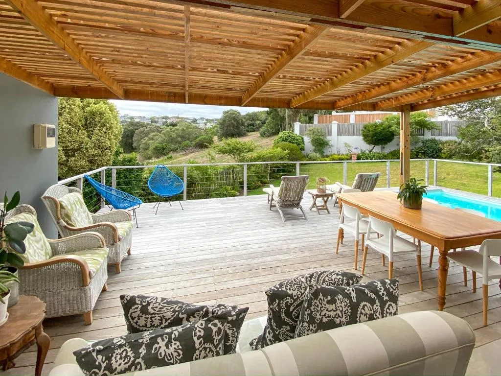 Spacious wooden deck with dining table, lounge chairs, and scenic garden views