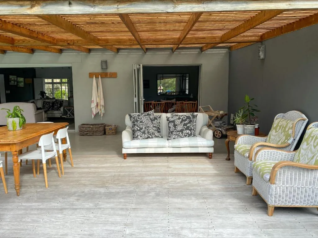 Spacious covered deck with wooden beams, lounge seating, and dining table