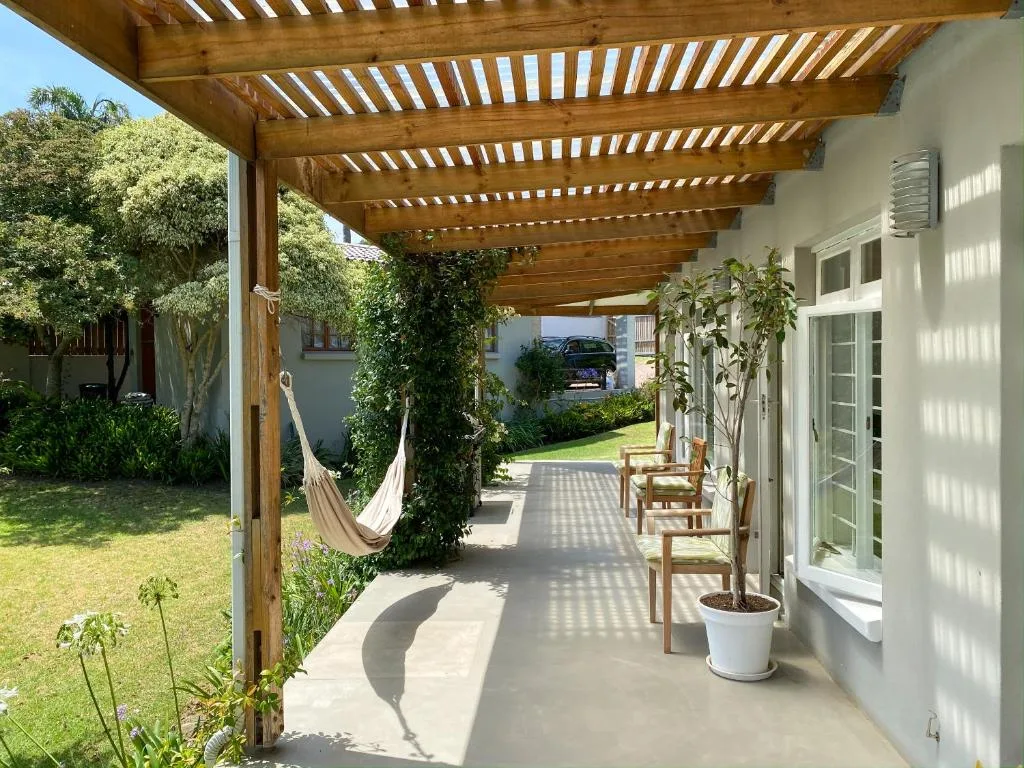 Wooden pergola deck with hammock, potted plants, and garden views