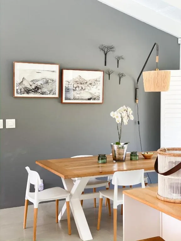 Modern dining area with wooden table, white chairs, framed artwork