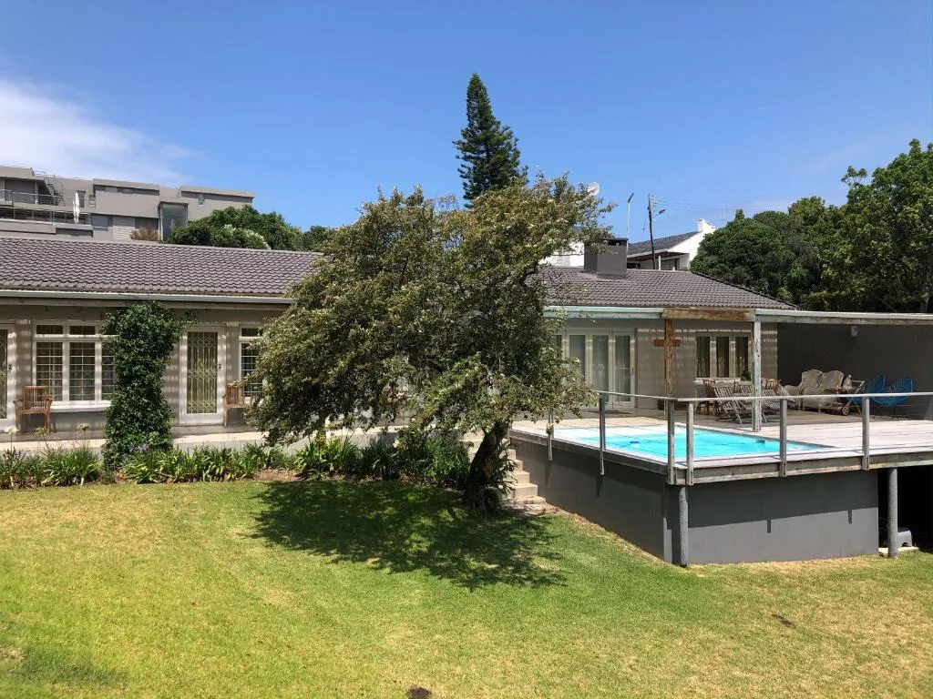 Modern home exterior with pool deck and manicured lawn garden