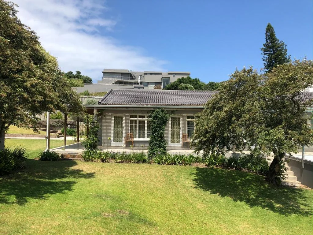 Modern home with covered porch, manicured lawns, and surrounding vegetation
