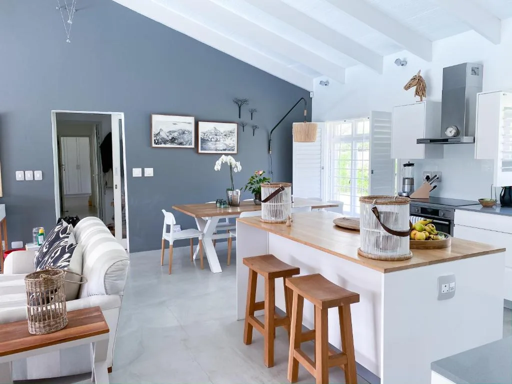 Modern open-plan kitchen with white cabinetry, wooden countertops, and bar seating
