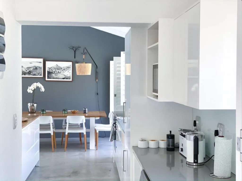 Modern kitchen with white cabinetry, gray countertop, and dining area beyond