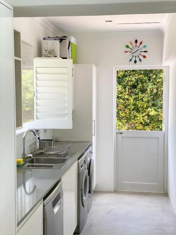 Compact galley kitchen with stainless steel sink, oven, and washing machine
