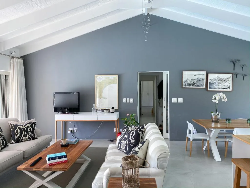 Modern lounge with grey walls, white sofas, wooden coffee table, and TV