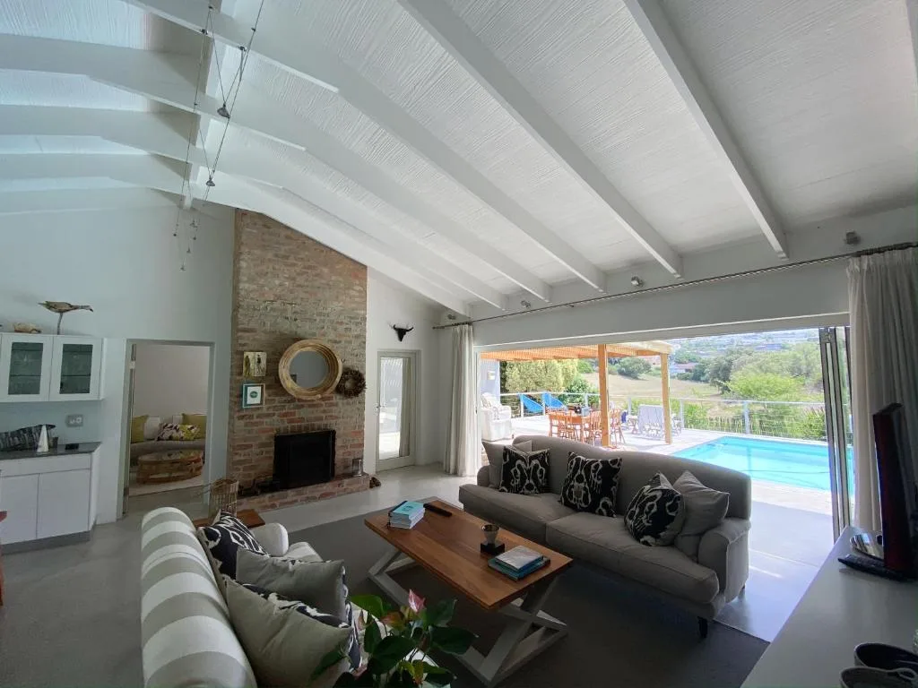 Modern lounge with fireplace, sofas, and pool view through glass doors