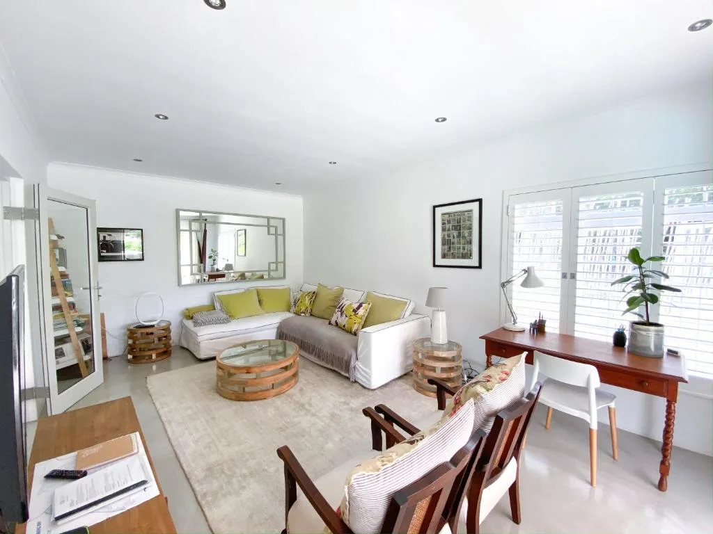 Bright open-plan lounge with white sectional sofa and yellow cushions