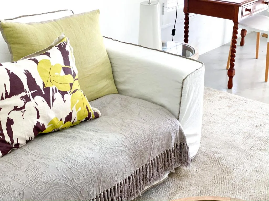 Bright lounge with cream armchair, colorful cushions, and wooden furniture