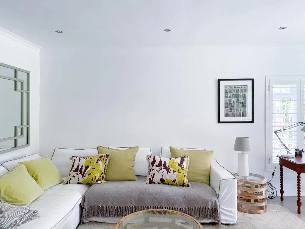 Bright living room with white sofa, yellow and patterned cushions, natural light