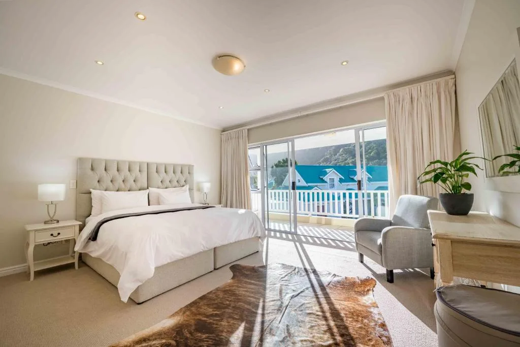 Bright bedroom with tufted headboard, ocean view through glass doors