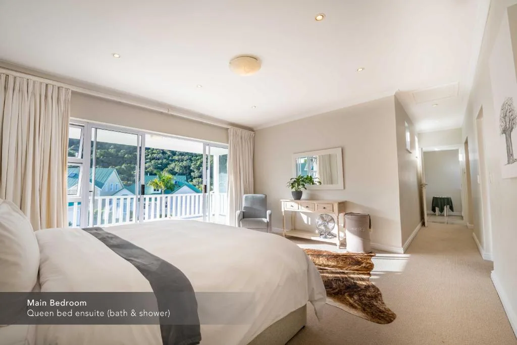 Spacious main bedroom with queen bed and scenic mountain views from balcony