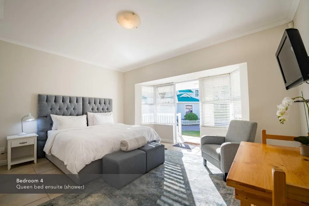 Spacious bedroom with queen bed, gray upholstered headboard, and garden views
