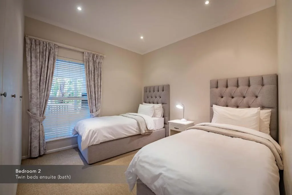 Spacious twin bedroom with upholstered headboards and garden view windows