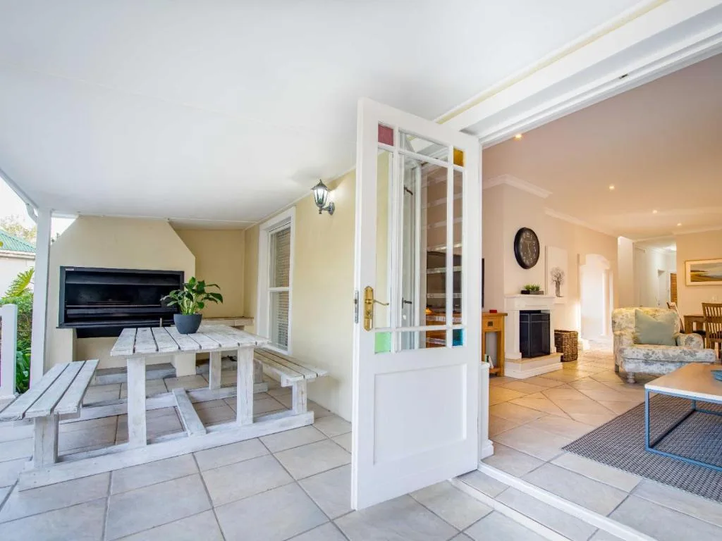 Covered patio with white picnic table and TV, opening to interior lounge