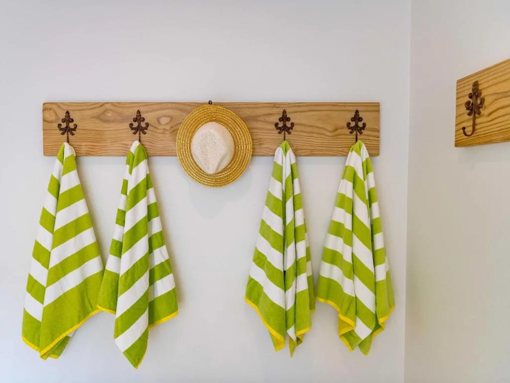 Decorative wooden rack with green striped towels and straw hat